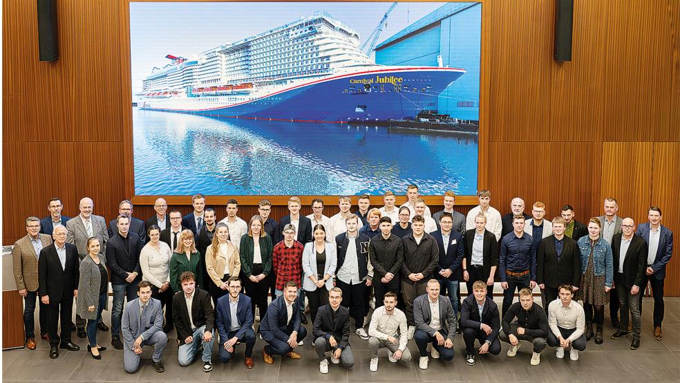 Vor einem großen Bild des Kreuzfahrtschiffes »Carnival Jubilee« versammelten sich die Auszubildenden und die Dualen Studenten der Meyer-Gruppe zu einem Erinnerungsfoto. Zweiter von links Seniorchef Bernard Meyer.  © Foto: Meyer Werft