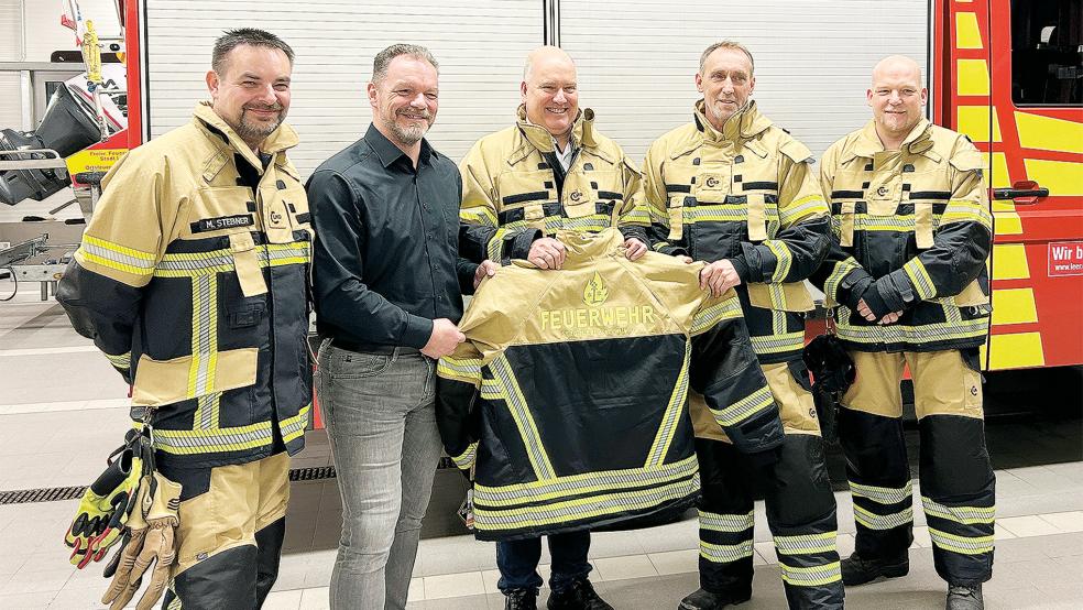 Martin Stebner von der Arbeitsgruppe, die die Anschaffung vorbereitete, Maik Größl (Vertriebsleiter der Herstellerfirma), Bürgermeister Claus-Peter Horst, Stadtbrandmeister Jan Doosje und sein Stellvertreter Jens Winkelmann (im Bild von links) mit der neuen Einsatzkleidung. Das Set besteht aus einer Überhose und einer Überjacke.  © Foto: Stadt Leer