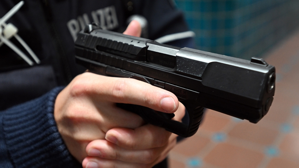 Ein Polizeibeamter seine Schusswaffe benutzt, um sich gegen einen aggressiven Hund zu schützen. © Gambarini (dpa/Symbolfoto)