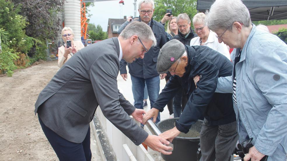 Ein Foto mit Symbolcharakter: Der Holocaust-Überlebende Albrecht Weinberg legt die Zeitkapsel in den Rohbau der neuen Bücherei. Unterstützt wird er dabei von seiner Lebensgefährtin Gerda Dänekas und Bürgermeister Heiko Abbas.  © Foto: Busemann