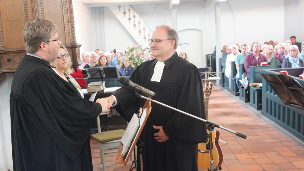 Präses Ard Nap gab Martin Schneider symbolisch die Hand, um ihn als Pastor einzuführen.  © Busemann