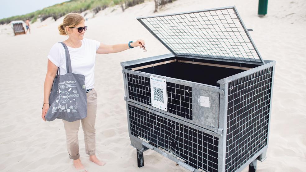 Nadine Weber trägt eine Strandmülltasche und wirft Abfall in die Strandmüllbox auf der Insel.  © Fotos: Dittrich/dpa