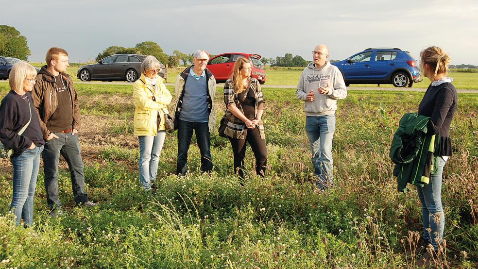 Am Rand dieses Feldes in Kanalpolder hat der Landwirtschaftliche Naturverein vor drei Jahren einen Blühstreifen angelegt. Fokko de Boer, zweiter Vorsitzender des Vereins (zweiter von rechts), erläuterte einigen Paten des Projektes am Montag weitere Einzelheiten.  © Foto: Hoegen