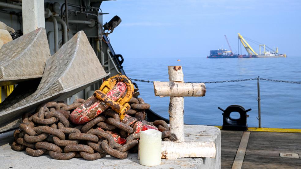 Ein Kreuz und eine Kerze zum Gedenken an die verstorbenen Seeleute der gesunkenen »Verity« stehen an Deck eines Schiffes, das an dem Bergungskran vorbeifährt.  © Schuldt (dpa/Archiv)