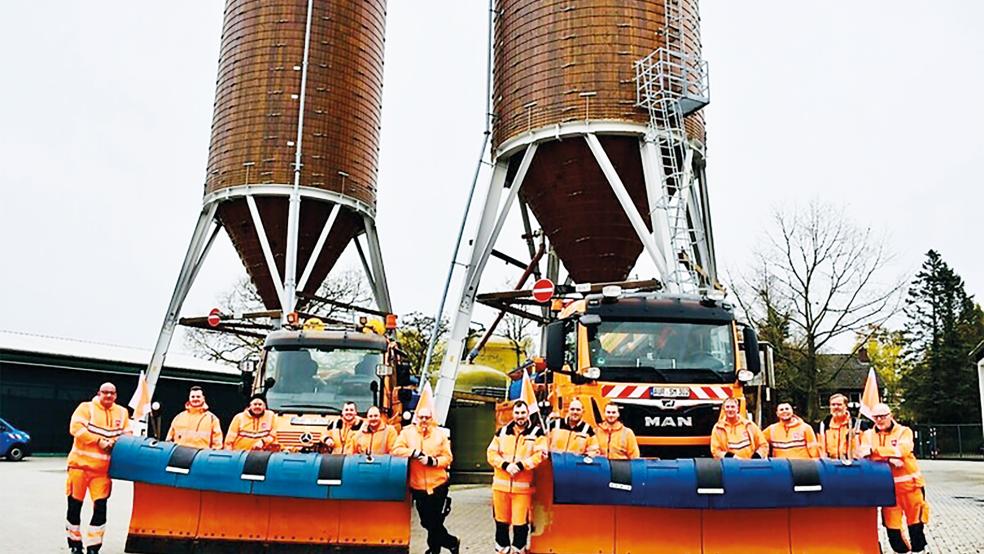 Sie sorgen auch im Winter für sichere Straßen: Ein Teil der insgesamt 25 Mitarbeitenden der Straßenmeisterei in Aurich. Hinter ihnen befinden sich zwei Silos, in denen das Streusalz gelagert wird.  © Foto: Landesbehörde für Straßenbau und Verkehr