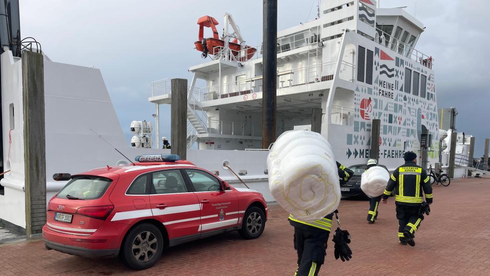 Schwer bepackt mit Ölsperren machen sich die Feuerwehrleute auf den Weg zur Fähre. © Feuerwehr Norden
