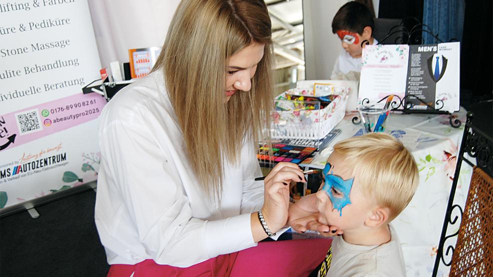 Kosmetikerin Alina Vasi schminkte auf ihrem Stand den zweijährigen Henry Sap aus Kirchborgum. Die Fachfrau hatte schon am ersten Gewerbeschautag gut zu tun. © Hoegen