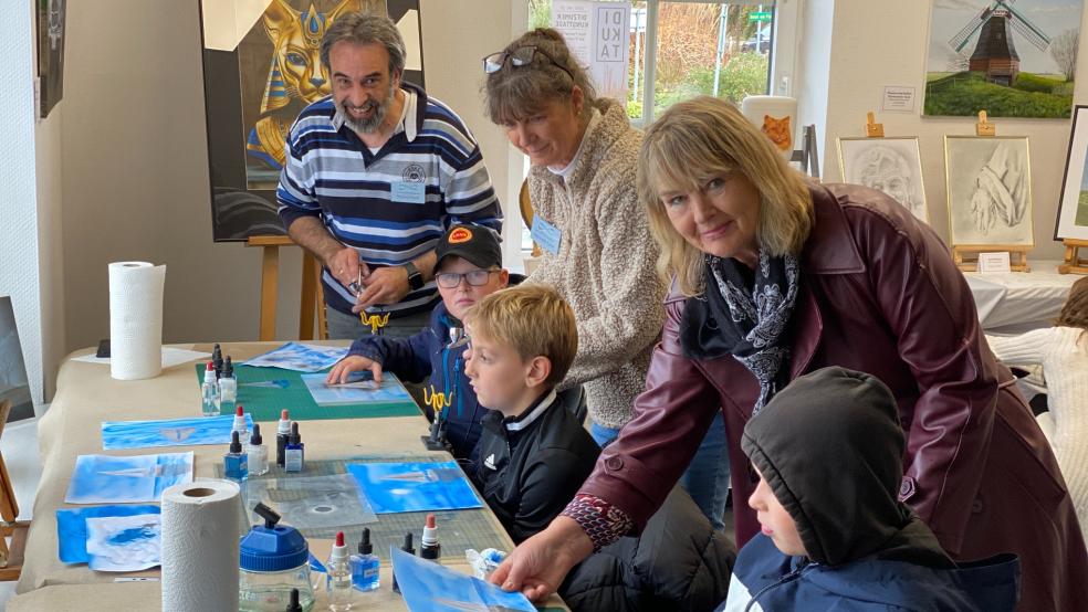 Carola Bruhns (rechts) als 2. Vorsitzende des Vereins Ditzumer Kunsttage freute sich im ehemaligen Baumarkt mit elf Ausstellern über die jungen Ditzumer Phillip (von vorne), Nils und Aiko, die am Airbrush-Workshop von Roland und Manuela Kuck teilnahmen. © Kuper