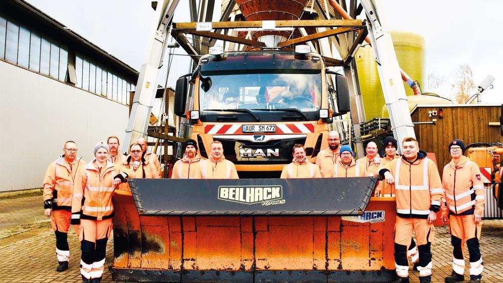 Sie sorgen auch im Winter für sichere Straßen: Die Mitarbeitenden der Straßenmeisterei in Leer. Hinter ihnen befinden sich zwei Silos, in denen das Streusalz gelagert wird.  © Foto: privat