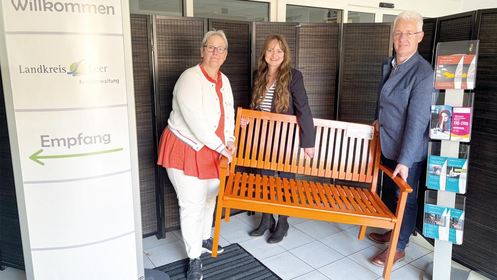 Landrat Matthias Groote (von rechts), Elke Engels (Gleichstellungsbeauftragte des Landkreises Leer) und Tomke Hamer (Gleichstellungsbeauftragte der Stadt Leer) tragen die Orangene Bank in den Vorraum des Kreisgebäudes in der Bavinkstraße.  © Foto: Landkreis Leer
