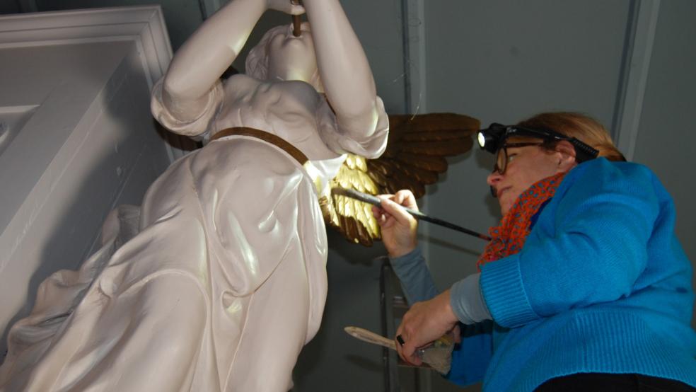 Anja Hänisch bei der Vergoldung eines Flügels des rechten Posaunenengels der Kirchenorgel. © Hoegen