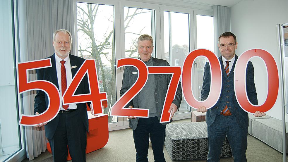 Mit ganz besonderen roten Zahlen operieren Carsten Rinne, Carsten Mohr und Ingo Fortkamp (von links) hier: Mit der Summe von 542.700 Euro hat die Sparkasse LeerWittmund im Jahr 2025 Projekte in ihrem Geschäftsgebiet unterstützt.  © Foto: Hoegen